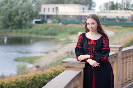 girl in national traditional ukrainian clothes. black and red embroidered dress. woman model posing in park outdoors.