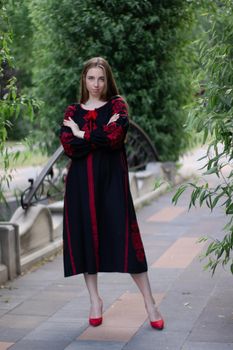 girl in national traditional ukrainian clothes. black and red embroidered dress. woman model posing in park outdoors.