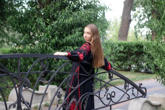 girl in national traditional ukrainian clothes. black and red embroidered dress. woman model posing in park outdoors.