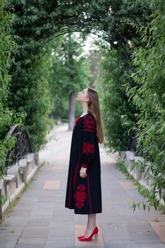 girl in national traditional ukrainian clothes. black and red embroidered dress. woman model posing in park outdoors.