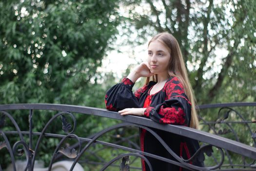 portrait of young woman wearing black and red vyshyvanka. national embroidered Ukrainian shirt. girl in dress outdoors in park. summer.