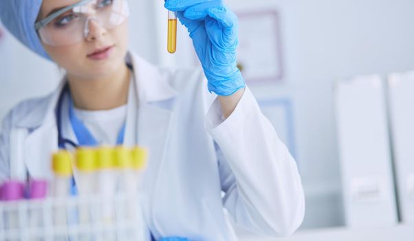 A female medical or scientific researcher or woman doctor looking at a test tube of clear solution in a laboratory .