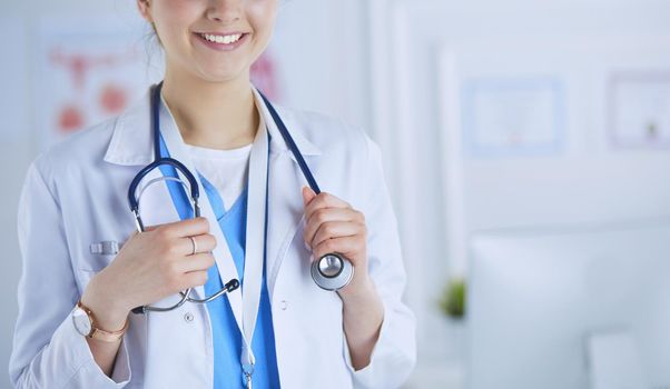Portrait of young woman doctor with white coat standing in hospital.