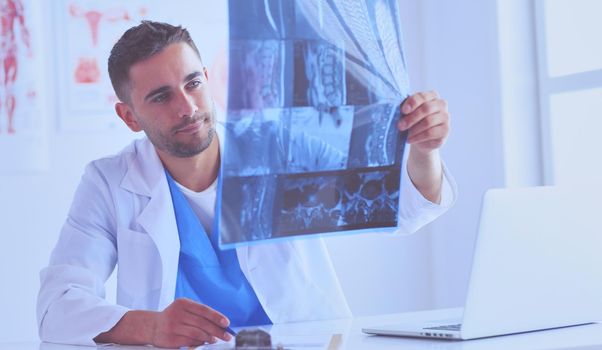 Handsome doctor is talking with young female patient and making notes while sitting in his office