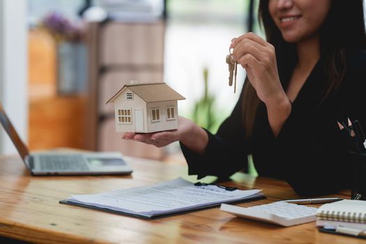 Close up Business woman or Real Estate agent giving house key after signing agreement for buying house. Bank manager and real estate concept