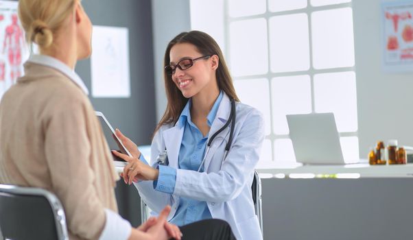 Doctor and patient discussing something while sitting at the table . Medicine and health care concept.