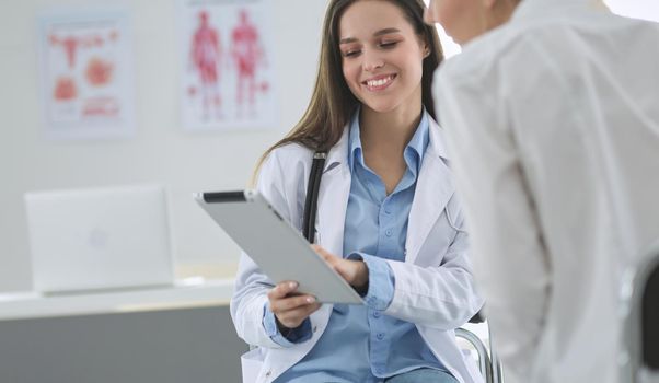 Doctor and patient discussing something while sitting at the table . Medicine and health care concept.