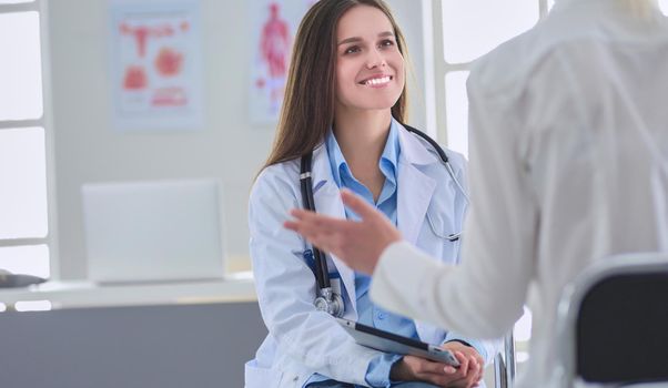 Doctor and patient discussing something while sitting at the table . Medicine and health care concept.