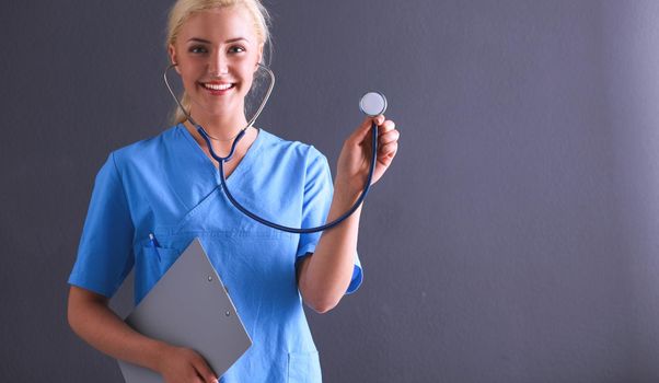 Female doctor with a stethoscope listening, isolated on gray background.
