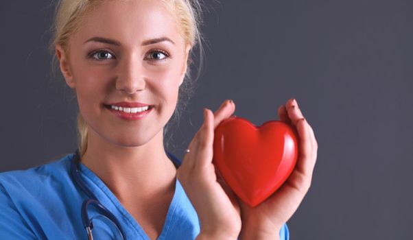 Young doctor woman with stethoscope holding heart .