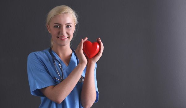 Doctor with stethoscope holding heart, isolated on gray background.