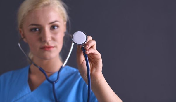 Female doctor with a stethoscope listening, isolated on gray background.