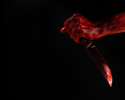 Man holding knife with bloody hand on black background