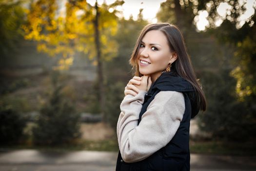 Portrait of a beautiful asian woman with brown hair in the forest in warm clothes in the fall outdoors. High quality photo