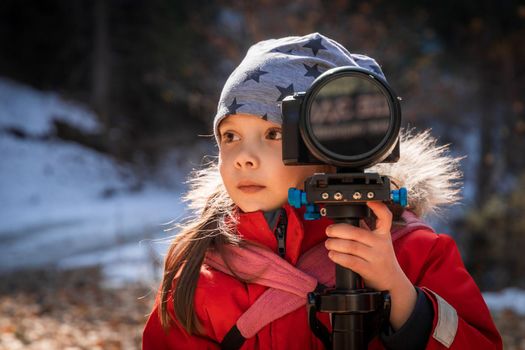 Little girl learning to take pictures with camera in nature.