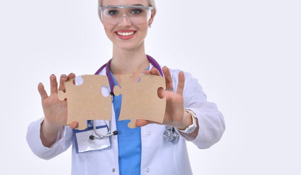 Woman doctor holding two connecting puzzle pieces.