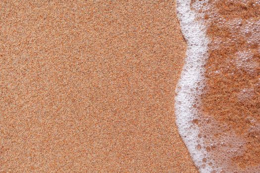 A soft wave runs on a sandy shore on a summer day. Empty space can be used as background for display or montage your top view products.