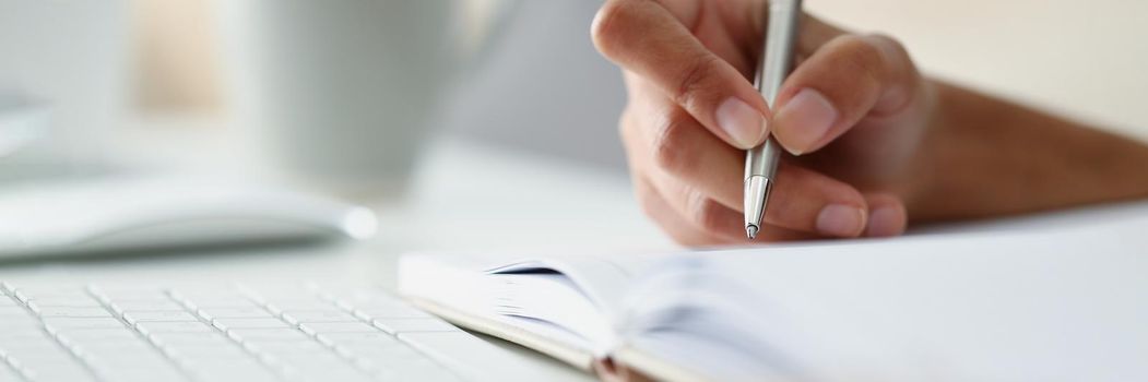 Close-up of persons hand writing down ideas in diary, notes for future, planning day in advance. Write with silver pen. Journal, creativity, writer concept