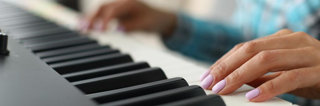 Close-up of womans hand touching white and black keyboards on piano. Talented girl playing song on musical instrument. Hobby, perform, solo, art concept