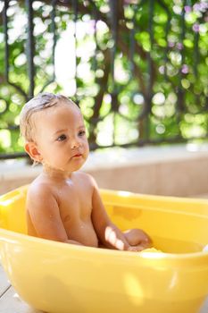 Little girl sits in a bowl of water. High quality photo