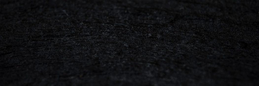 Texture of black old wood. Close-up of the texture of deep black bog oak. Sinuous wood texture with shadow