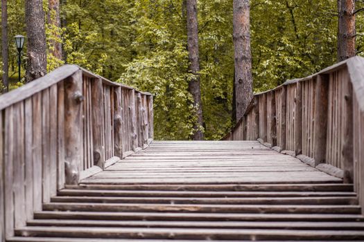 Wooden, pedestrian bridge across the river in the park or in the forest. Bridge and walking path.