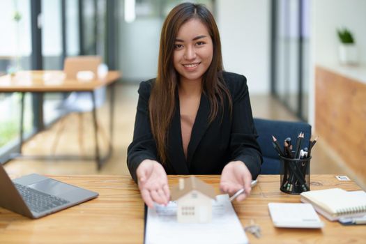 Portrait of an Asian female bank employee asking a customer to read the contract before signing to agree to buy a house, real estate concepts.