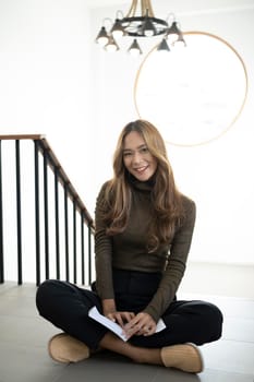 Portrait of beautiful asian woman sitting in living room and smiling on camera.