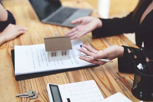 Asian female bank employee asking a customer to read the contract before signing to agree to buy a house, real estate concepts.