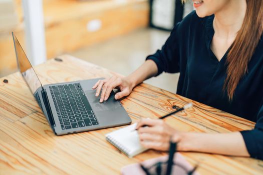 A portrait of an Asian teenage girl using a computer while sitting at work looking for new ideas and projects.