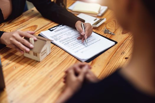 Asian female bank employee asking a customer to read the contract before signing to agree to buy a house, real estate concepts.