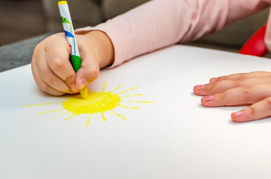 Education and school. Education and kindergarten concept. Cute little girl draws the sun with pencils.