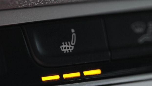 Turning on the seat heating button in the car. Switching ON heated seats of car by pressing the buttons. Heated seat dashboard in a car