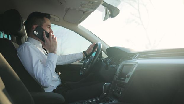 Businessman is talking on his Smart Phone while traveling in Business Class Car. Successful Lifestyle. Young Businessman Talking On Mobile Phone In A Car.