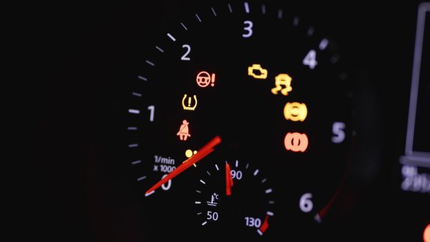 Tachometer Gauge of Starting and Stopping Car. Starting car engine. Dashboard in the car. Many different car dashboard lights with warning lamps illuminated.