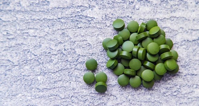 Green pills of chlorella and spirulina. Selective focus drink
