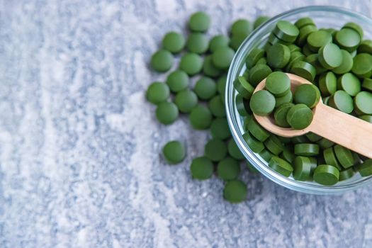 Green pills of chlorella and spirulina. Selective focus drink
