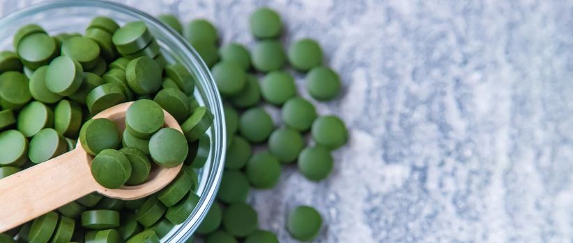 Green pills of chlorella and spirulina. Selective focus drink