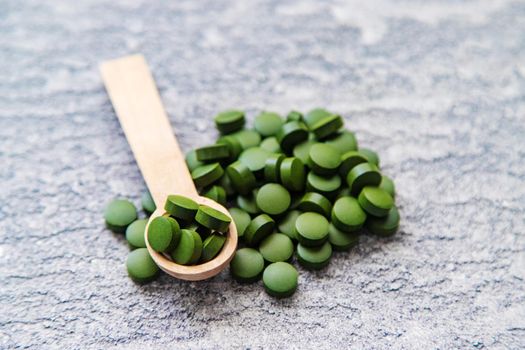 Green pills of chlorella and spirulina. Selective focus drink