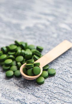 Green pills of chlorella and spirulina. Selective focus drink