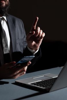 Man Holding Mobile Phone In Hand And Pointing With One Finger On Data.