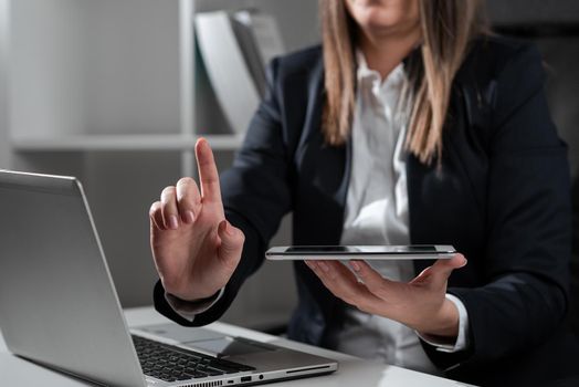 Woman Holding Tablet In One Hand And Pointing On News With One Finger.