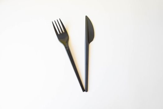 Top view of black plastic disposable fork and knife isolated on white.