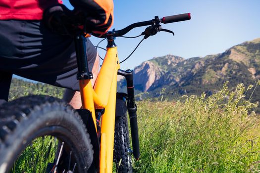 close up of a man observing the landscape and the mountains standing next to his mountain bike in the countryside, concept of sport and healthy lifestyle in nature, copy space for text