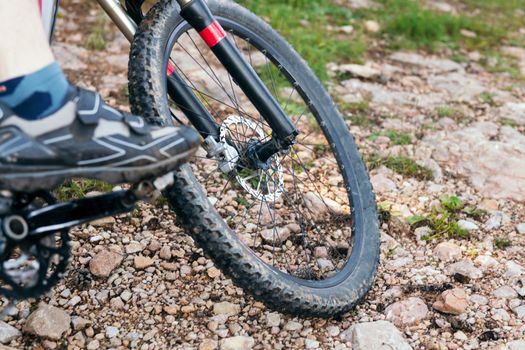 detail of a mountain bike wheel on a rocky terrain, concept of sport and healthy lifestyle