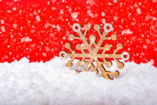 Snow on a red background, snowfall or falling snow. Large wooden snowflake in the snow. Christmas concept. New Year theme, panoramic photo for a banner or website header. Christmas card