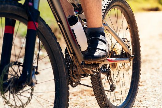 close up of the wheels of a mountain bike on a dirt road, concept of sport and healthy lifestyle in nature