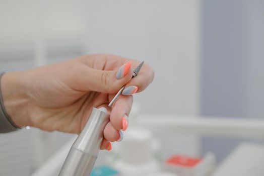 Woman changes the cutter on the machine for manicure