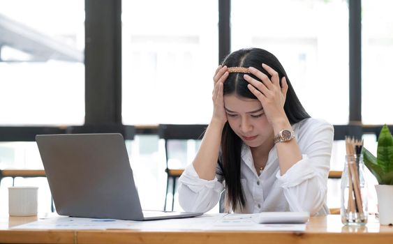 Image of an Asian business woman is stressed, bored, and overthinking from working on a tablet at the office..