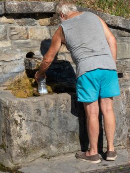 Drink spring water pouring in to bottle over sunlight and natural background in Piacenza Italy